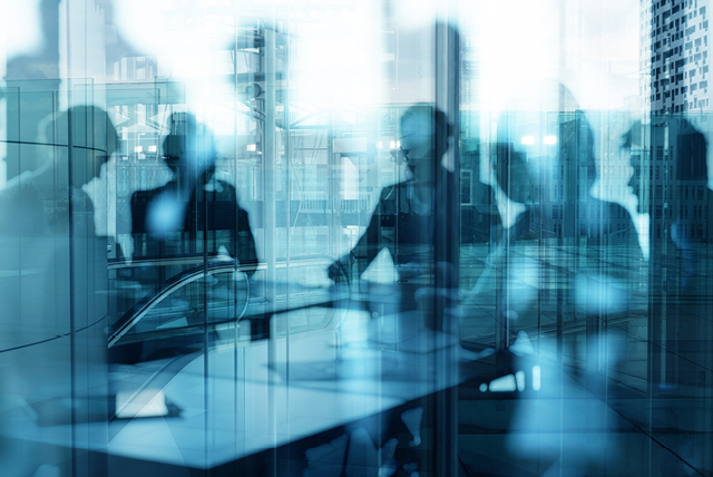 blurred blue texture of corporate setting with people sat around a meeting table