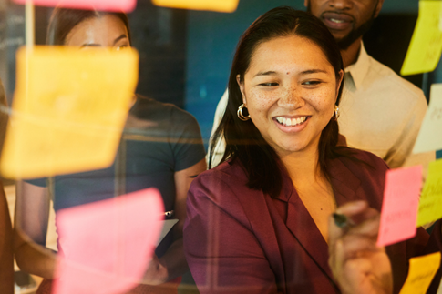 Industry Reports : CLI Future of Law - Professional Office Worker smiling while writing on a sticky note